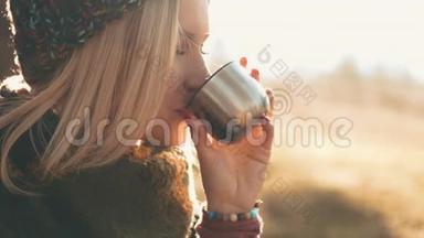 女人打开一个瓶子，喝着一顶帽子里的咖啡